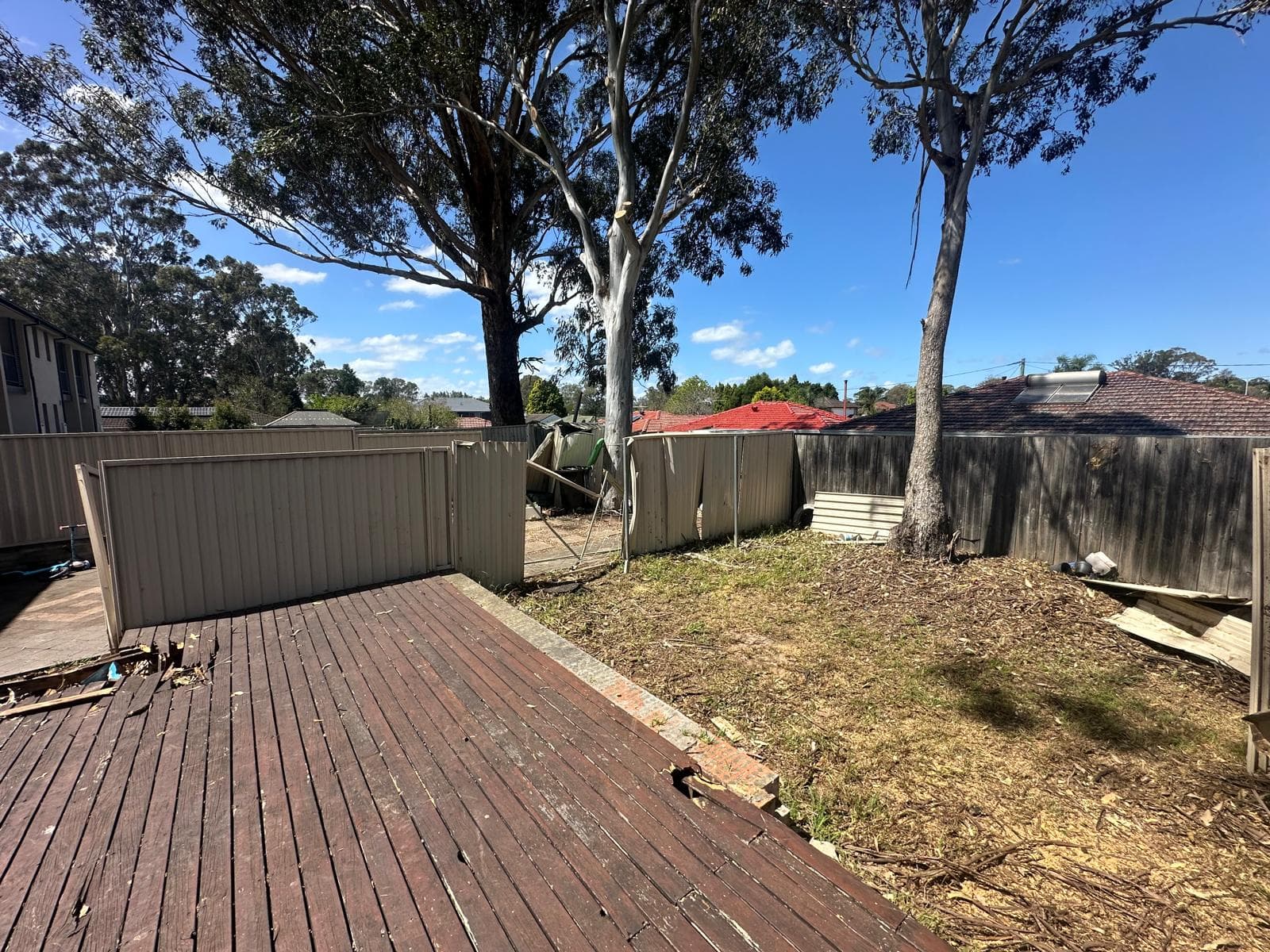 After removal: the open backyard beside the damaged deck and boundary fencing in Toongabbie.