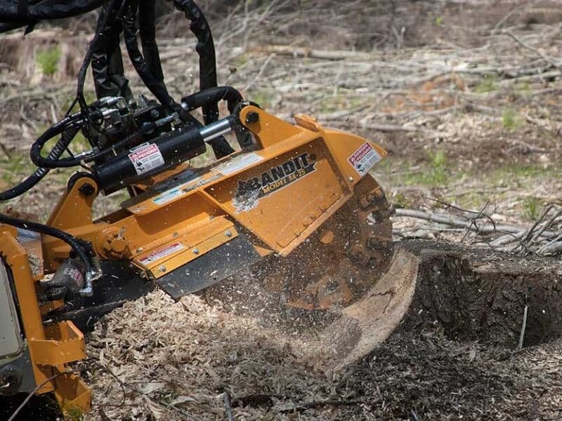 Stump grinder cutting into a stump, with wood chips beside it.